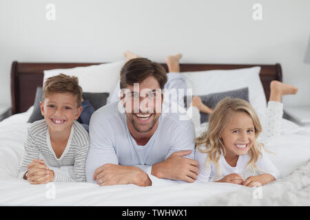 Vater und Kinder zusammen liegend auf Bett im Schlafzimmer zu Hause Stockfoto