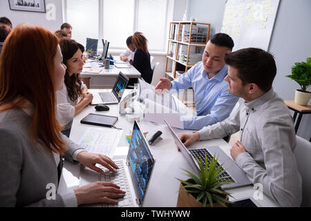 Kaufmann und Kauffrau gemeinsam diskutieren in einer Sitzung während der Verwendung von Laptops Stockfoto