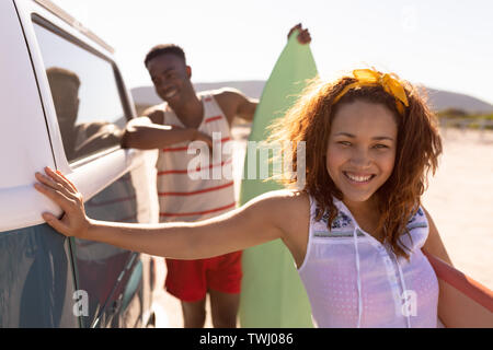 Verschiedene Freunde sind bereit zum Surfen und lächeln am Strand Stockfoto