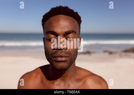 Mann mit geschlossenen Augen stehen am Strand in der Sonne Stockfoto