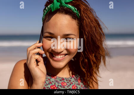 Schöne Frau Gespräch am Handy am Strand in der Sonne Stockfoto