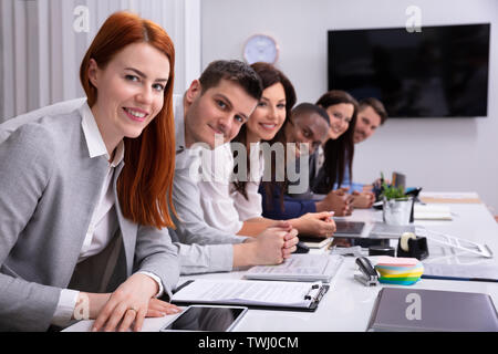 Multiethnische Gruppe von Happy Geschäftsleute zusammen In der Reihe sitzen an Kamera suchen Stockfoto