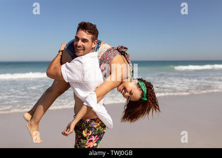 Mann, der Frau auf den Schultern am Strand in der Sonne Stockfoto