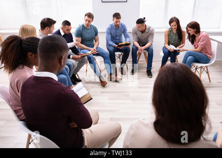 Gruppe Junger multi-ethnischen Menschen Lesen der Bibel zusammen Stockfoto