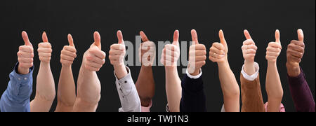 Close-up von Menschen Hand, Daumen hoch, Zeichen auf schwarzem Hintergrund Stockfoto