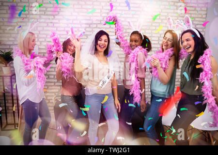 Fröhlicher junger Freunde feiern Bachelorette Party der Braut gegen Mauer Stockfoto