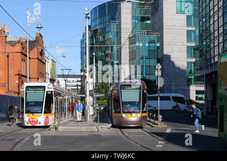 Busaras LUAS in Store Street, Dublin, mit zwei LUAS-Straßenbahn und Pendler an einem sonnigen Sommerabend in Dublin, Irland. Stockfoto