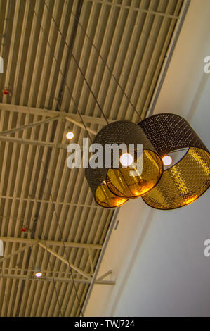 Modern bronze dekorative Lampen und Golden Lampenschirme hängen an einem langen Seil, industriellen Decken, Innenausbau vertikale erschossen. Stockfoto