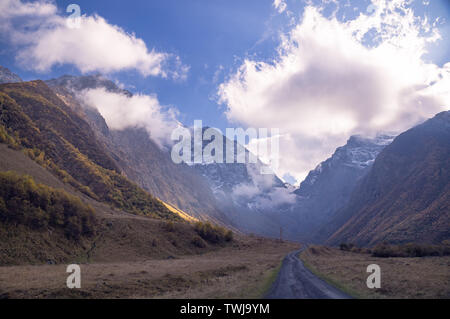 Majestic Mountain View - felsige Gipfel mit Schnee Patches auf den Horizont mit bräunlich Herbst montains vorne und der Weg in die Schlucht unter Stockfoto