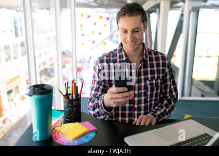 Männliche Grafik Designer mit Handy und Laptop am Schreibtisch arbeiten Stockfoto