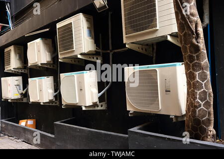 Gruppe der verflüssigungssätze von Klimaanlagen an der Wand hinter Gebäude fest, selektiver Fokus Stockfoto