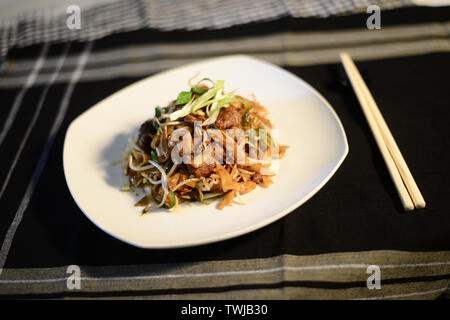 Chinesisch gebratener Reis Nudeln mit Rindfleisch, die Einrichtung schön auf dem Tisch bereit zu dienen Stockfoto