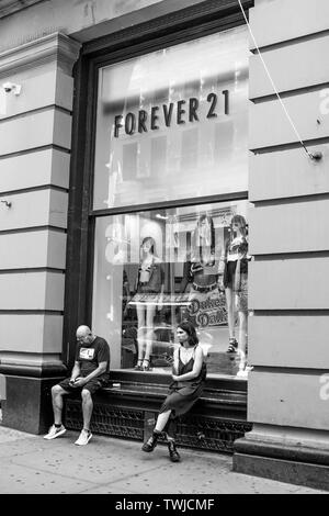 New York, 6/15/2019: Ein paar Leute sitzen vor einem Fenster eines Für Immer 21 Stores in SoHo. Stockfoto