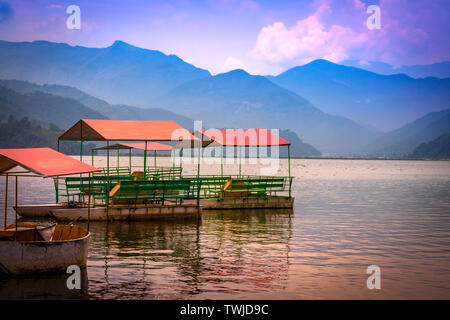 Bunte Tretboote geparkt In Phewa See, Blue Hills und Sonnenuntergang Wolken im Hintergrund Pokhara Nepal. Stockfoto