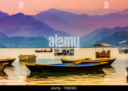 Bunte Tretboote geparkt In Phewa See, Blue Hills und Sonnenuntergang Wolken im Hintergrund Pokhara Nepal. Stockfoto