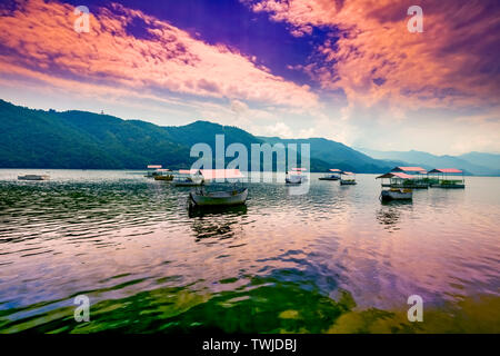 Bunte Tretboote geparkt In Phewa See, Blue Hills und Sonnenuntergang Wolken im Hintergrund Pokhara Nepal. Stockfoto