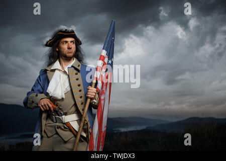 Soldat der United States Unabhängigkeitskrieg mit Fahne und Pistole über dramatische Himmel posieren. 4. Juli Geschichte Konzept Foto Stockfoto