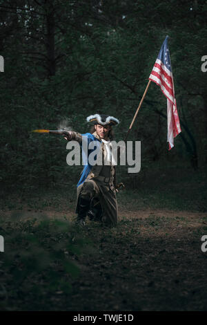 Epische Portrait von Menschen als Soldat der amerikanischen Revolution Krieg der Vereinigten Staaten gekleidet zielt darauf ab, Pistole mit Fahne. 4. Juli, Tag der Unabhängigkeit der USA Konzept Stockfoto