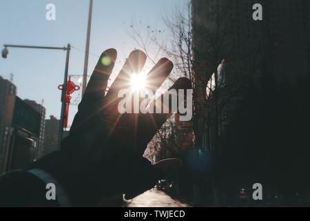 Die Sonne scheint durch die Lücke zwischen den Fingern. Stockfoto