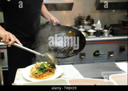 Nahaufnahme von Koch die Nudeln auf einem Teller aus dem Wok, chinesisch Takeaway, asiatische Küche, Küche. Stockfoto