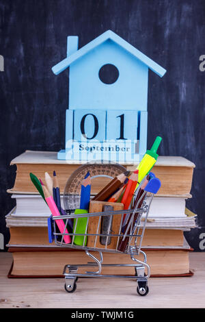Satz farbiger Stifte und Marker für die Schule in einen Warenkorb. 1 September Kalender auf Stapel Bücher Stockfoto