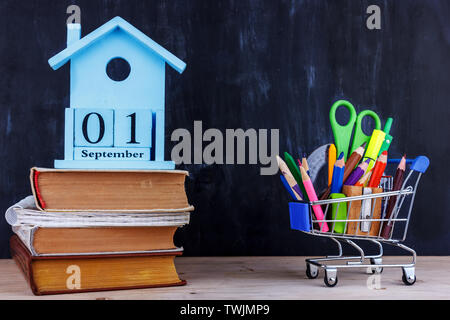Satz farbiger Stifte und Marker für die Schule in einen Warenkorb. 1 September Kalender auf Stapel Bücher Stockfoto