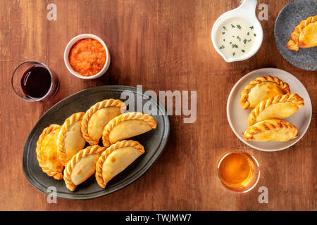 Empanadas mit Saucen und Wein, Schuß von der Oberseite in einem dunklen Holzmöbeln im Landhausstil Hintergrund mit einem Platz für Text Stockfoto