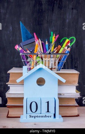 Satz farbiger Stifte und Marker für die Schule in einen Warenkorb. 1 September Kalender auf Stapel Bücher Stockfoto