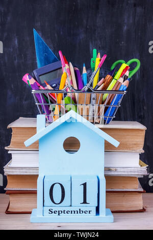 Satz farbiger Stifte und Marker für die Schule in einen Warenkorb. 1 September Kalender auf Stapel Bücher Stockfoto