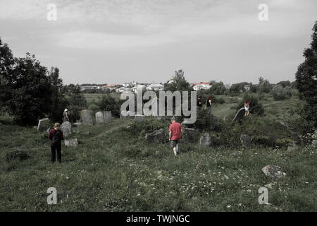 Die Teilnehmer der ROOTKA-Reiseagentur, die sich auf jüdische Kulturreisen in Osteuropa spezialisiert hat, wandern auf dem jüdischen Friedhof, der als ältester Aschkenazi-Friedhof in der Ukraine und einer der ältesten in Mittel- und Osteuropa gilt, unter alten Grabsteinen aus dem Jahr 1520, In der Stadt Busk, die einst die Heimat einer großen jüdischen Gemeinde war und während des Zweiten Weltkriegs von den Deutschen vernichtet wurde, befindet sich im Bezirk Busk im Gebiet Lwiw (Region) der Westukraine. Stockfoto