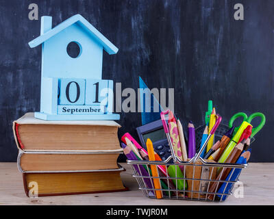 Satz farbiger Stifte und Marker für die Schule in einen Warenkorb. 1 September Kalender auf Stapel Bücher Stockfoto