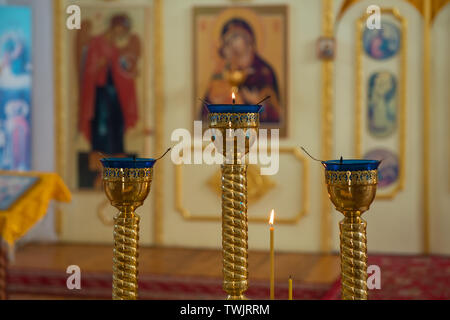 Lampen und Kerzen vor dem Altar einer orthodoxen Kirche Stockfoto