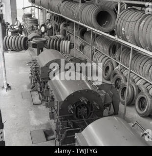 1950er Jahre, historische Bild aus dieser Ära, die in einem Fahrzeug reifen Werk, England, UK angezeigt, mit der Reifenherstellung Maschinen und mehrere Reihen von Reifen Regal gestapelt. Stockfoto