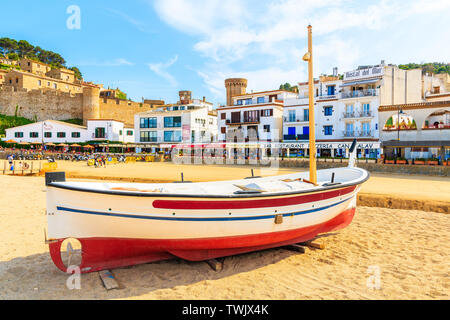 TOSSA DE MAR, SPANIEN - Jun 3, 2019: Fischerboot auf goldenen Sandstrand von Lloret de Mar Stadt mit bunten Häuser im Hintergrund, Costa Brava, Spanien. Stockfoto