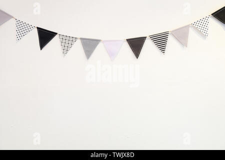Kleine schwarze weiße Dreieck Form Flagge aufhängen Kurve nach unten Pflasterwand auf weißem Hintergrund Stockfoto