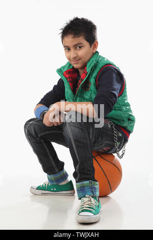 Junge sitzt auf einem basketball Stockfoto