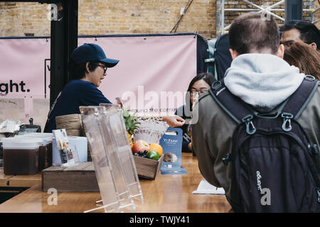 London, UK, 15. Juni 2019: Mann kaufen Taiwan Obst Tee aus Yi Fang stall in Spitalfields Market, einem der schönsten viktorianischen Märkten in London Stockfoto