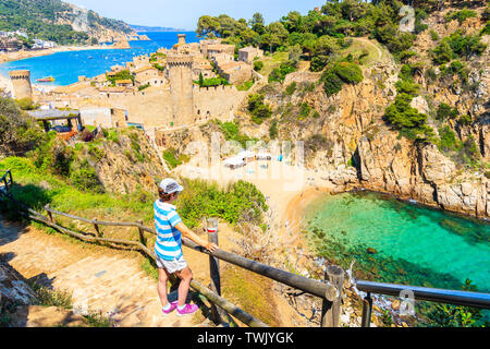 Junge Frau touristische stehend auf Küste und mit Blick auf Strand und Bucht von Tossa de Mar, Costa Brava, Spanien Stockfoto