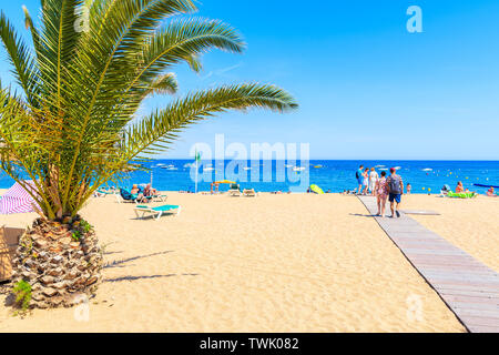 TOSSA DE MAR, SPANIEN - Jun 3, 2019: Menschen zu Fuß am Sandstrand in Tossa de Mar, Costa Brava, Spanien. Stockfoto