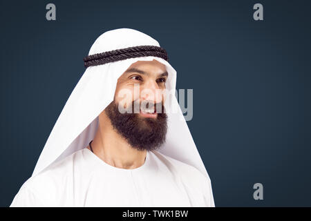 Brustbild des Arabischen saudischen Geschäftsmann auf dunkelblau studio Hintergrund. Junge männliche model posing und lächelnd, sieht glücklich aus. Konzept der Business, Finanzen, Mimik, menschliche Gefühle. Stockfoto
