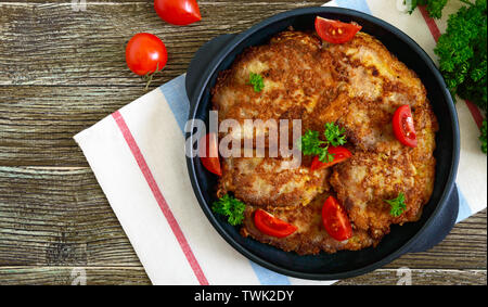 Lecker Schweinfilet, auf eine Besetzung dienen - eiserne Pfanne auf einem Holztisch. Schnitzeln. Ansicht von oben, flach. Stockfoto