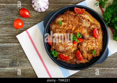 Lecker Schweinfilet, auf eine Besetzung dienen - eiserne Pfanne auf einem Holztisch. Schnitzeln. Ansicht von oben, flach. Stockfoto