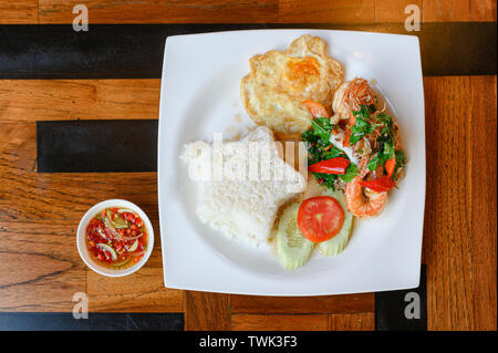 Wokgemüse Basilikum, Chili mit Garnelen, Tintenfisch mit Spiegelei und weißer Reis auf dem Teller Stockfoto