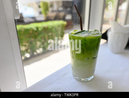 Iced Matcha grüner Tee mit Milch mit Stroh im Glas auf dem Tisch Stockfoto