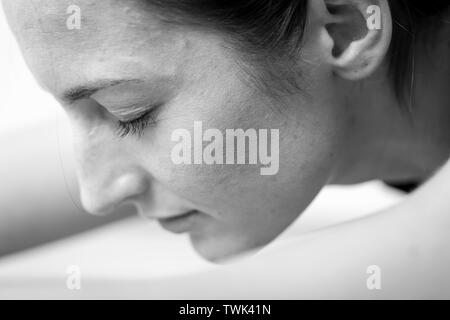 Close-up Seite Blick auf eine junge Frau auf einem sitzend/nach vorne beugen oder Schlafen Swan Asana oder Yoga dar. Stockfoto