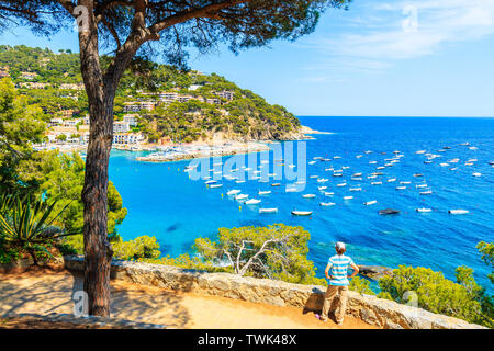 Junge Frau touristische stehend auf Sicht auf die herrliche Bucht mit Booten auf das Meer in der Nähe von Llafranc Dorf, Costa Brava, Spanien Stockfoto