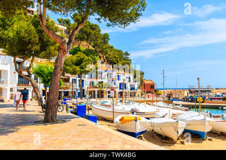 Junges Paar von Menschen zu Fuß im Hafen von Llafranc Dorf mit Fischerbooten am Strand, Costa Brava, Spanien Stockfoto