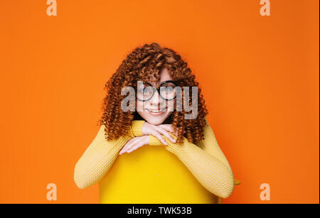 Porträt eines lächelnden Curly rothaarige Frau mit trendigen Brillen auf orange Hintergrund Stockfoto