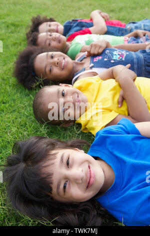 Gruppe von Kindern auf dem Rasen liegend Stockfoto