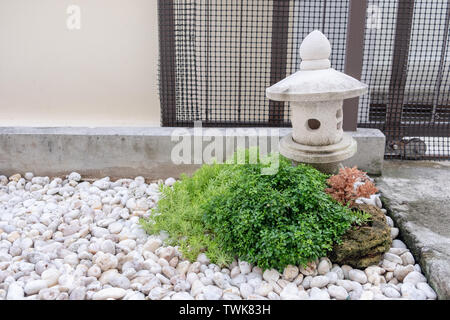 Dekorative garten Stein Laterne mit Green Bush am White Rock Stockfoto